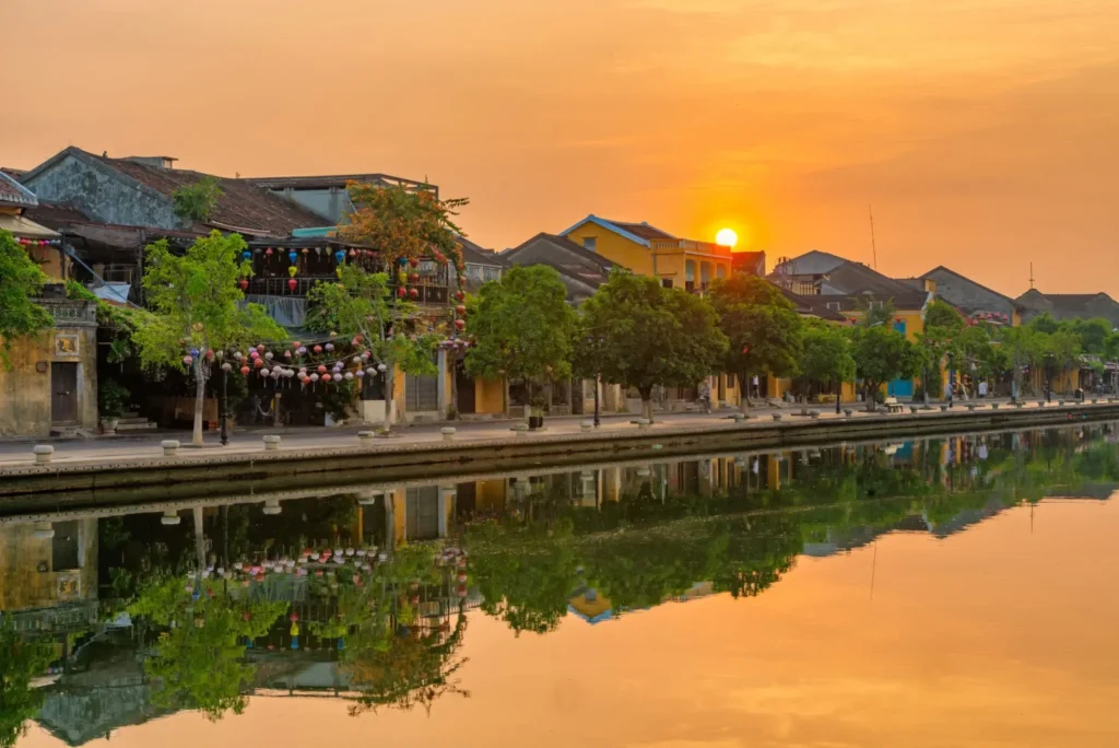 A female traveler capturing photos of the iconic yellow heritage buildings in Hoi An Ancient Town during a warm golden hour.