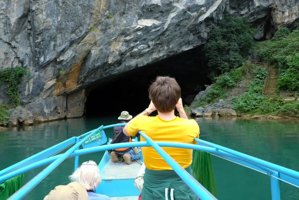 An independent female traveler exploring the entrance of a massive limestone cave formation in Phong Nha-Ke Bang National Park, Vietnam.