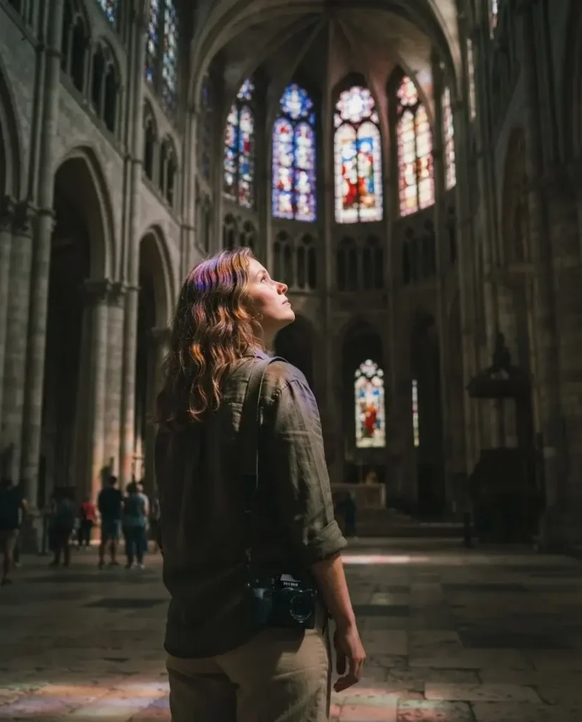 Solo traveler looking up at medieval stained glass windows inside Chartres Cathedral, France